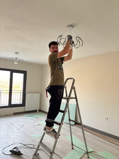 Konut içinde avize montajı yapan elektrikçi